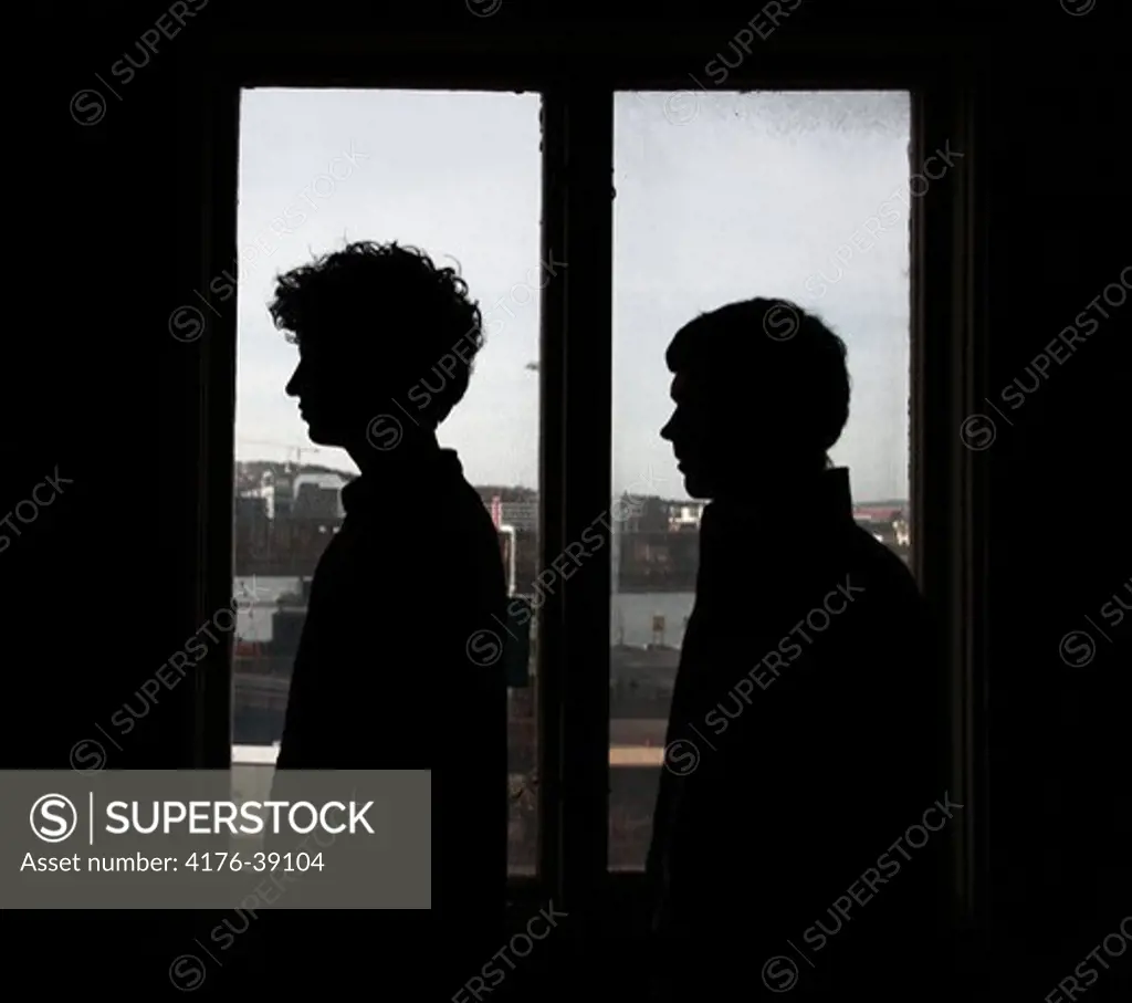 Two young men standing by a window, Gothenburg (Goteborg), Sweden.