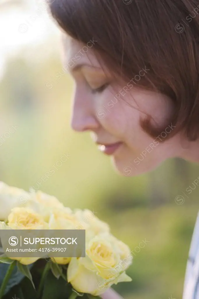A woman scenting yellow roses