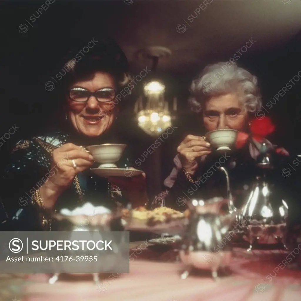 Two dressed up women drinking tea