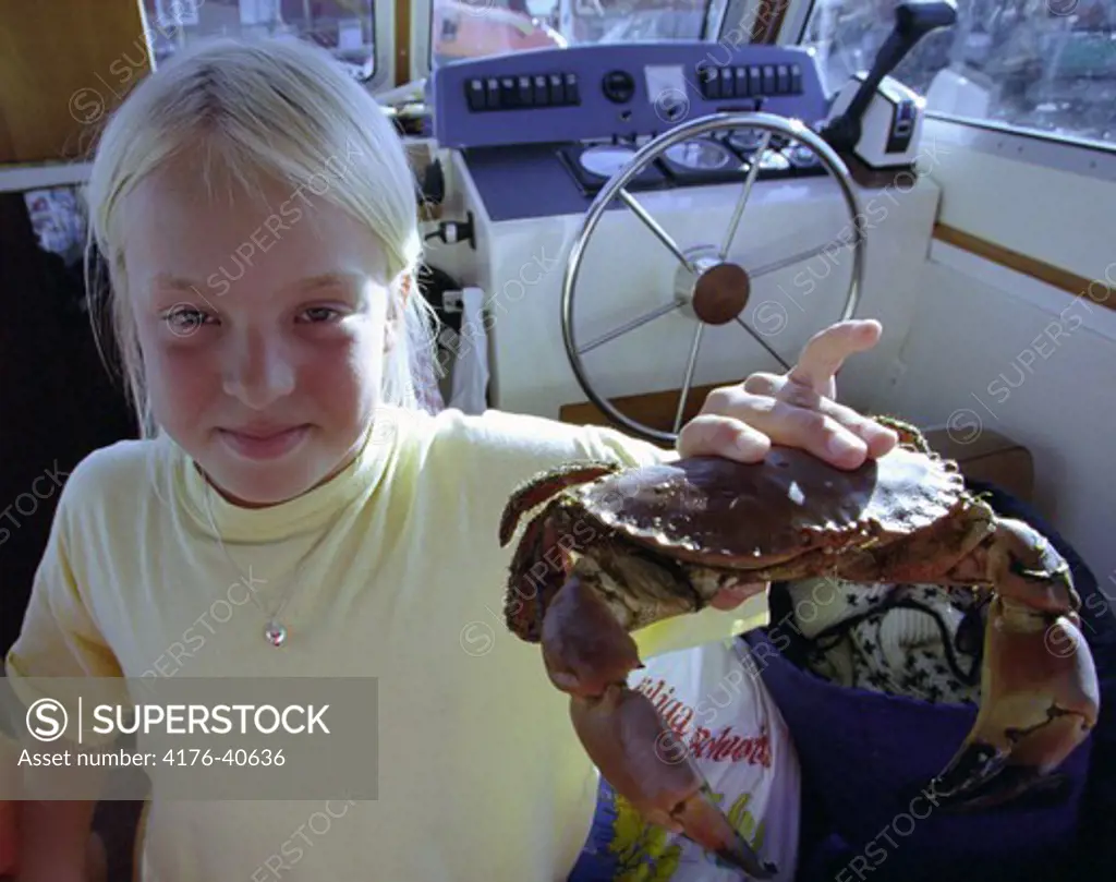 A girl in the cabin of a boat holding a crab - Flicka som hŒller en krabba