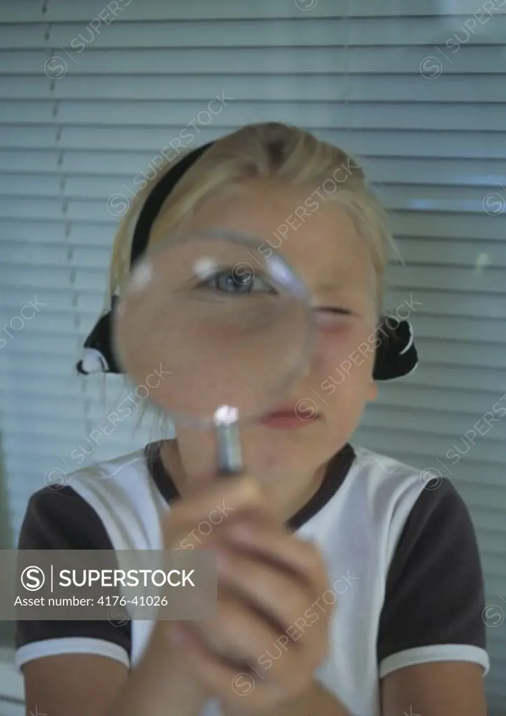 Flicka visar sitt šga genom ett fšrstoringsglas