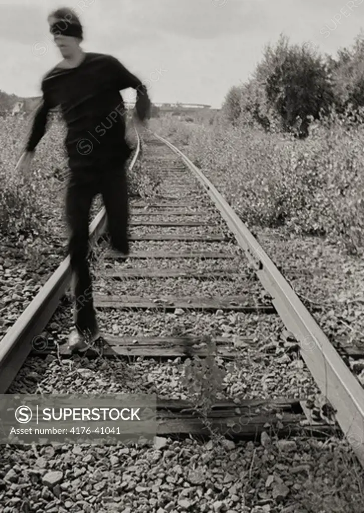 A man with adjuncted eyes running on a railway track