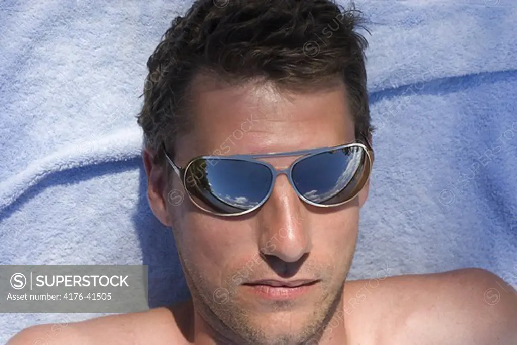 Sun bathing man in mirror sunglasses