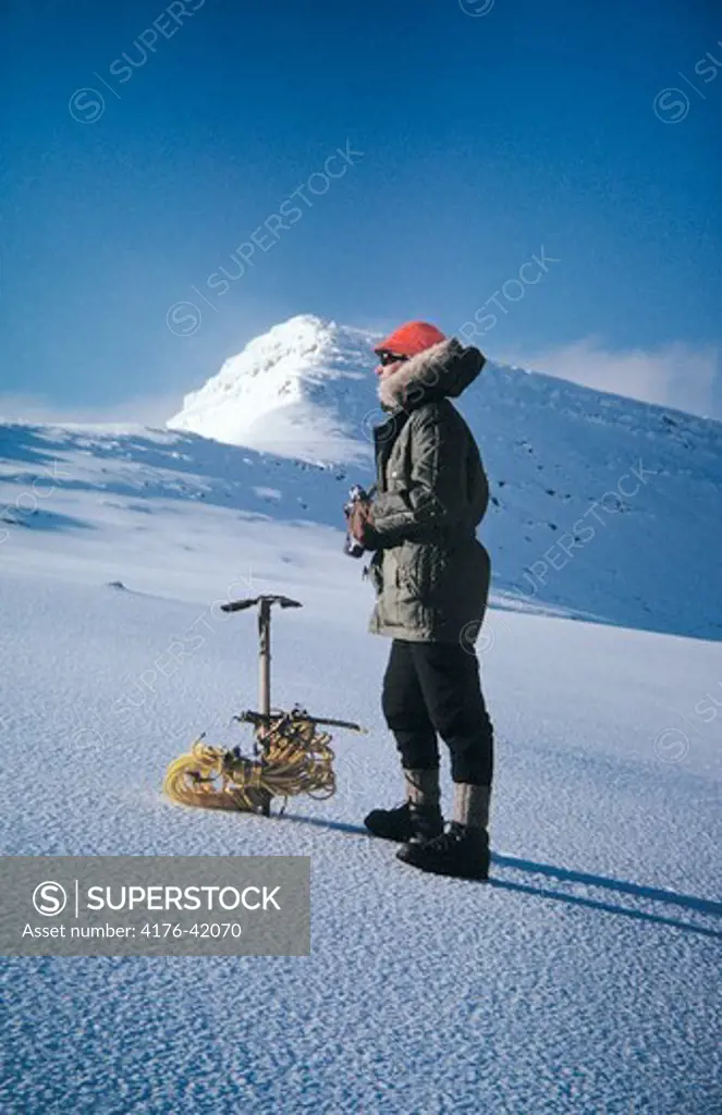 A hiker resting in a snowy hill, mountain in background