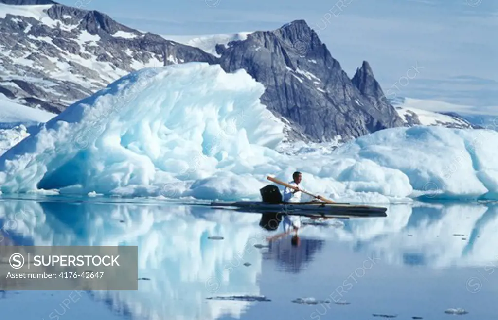Person sailing a kajak with iceberg in the background
