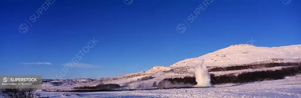 Snowy landscape and an erupting geyser