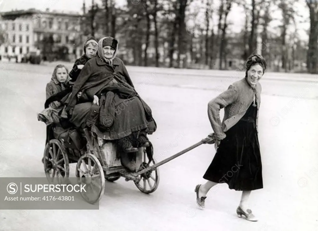 A woman pulls a cart with an older woman and two children