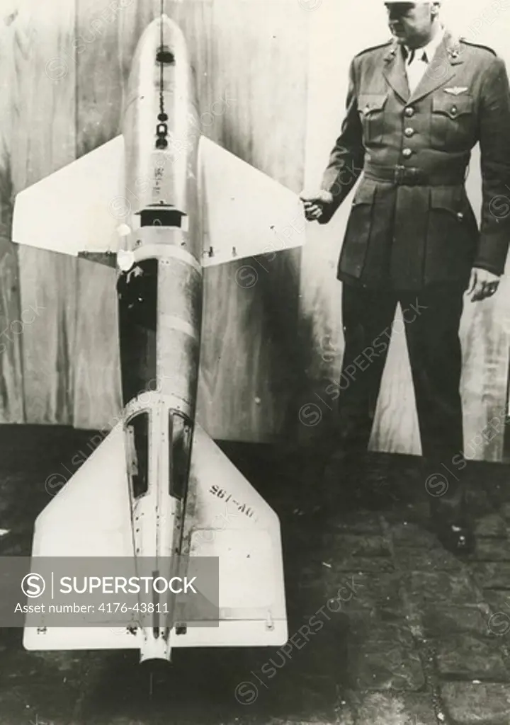 A man stands next to a winged bomb