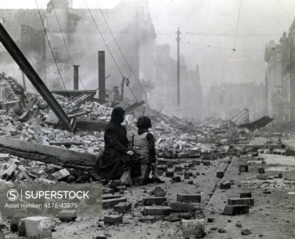 People sitting amidst war ravaged buildings