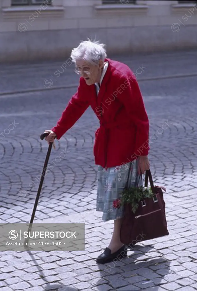 An old hunched woman walking at a pedestrian