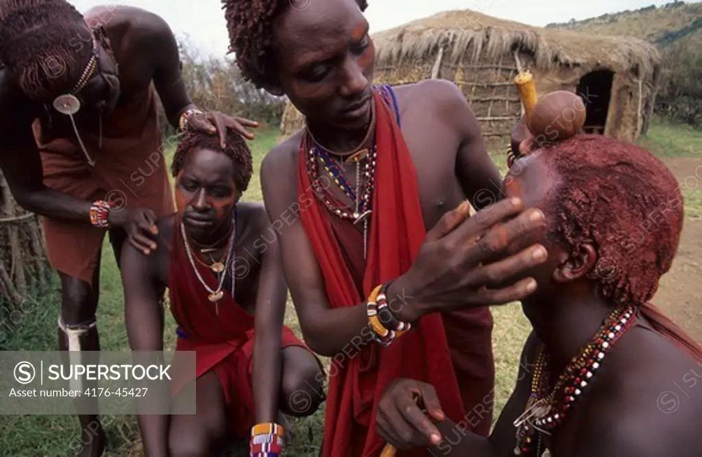 A Maasai warrior o Moran applying a mixture of ochre on lambs fat.