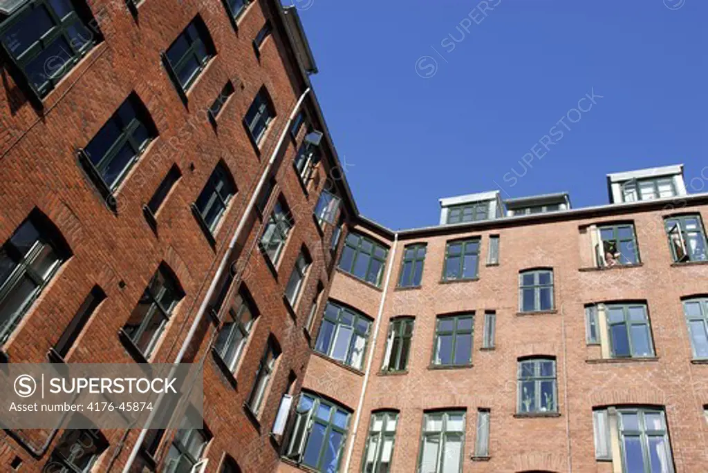 Woman waving from apartment on fourth floor, Copenhagen, Denmark.