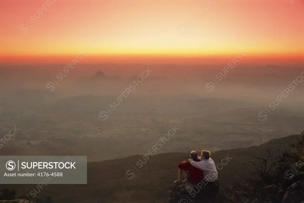 Couple sitting over the Eastern Highlands of Zimbabwe at sunset