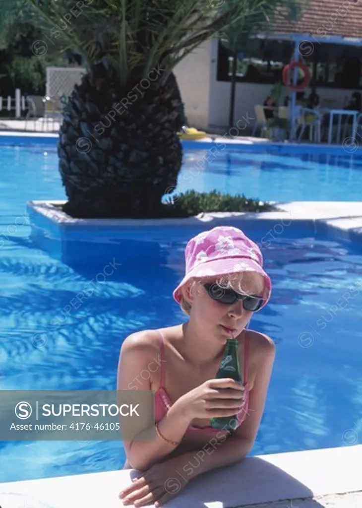 A girl drinking a soda in a swimming pool