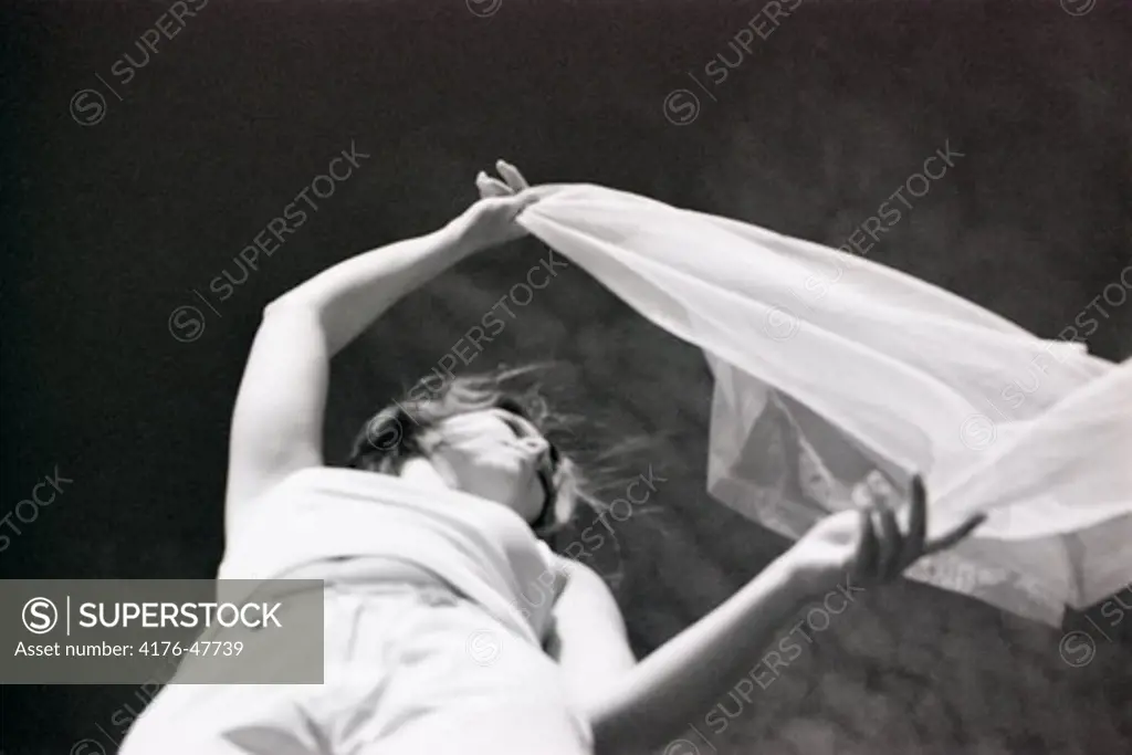 A girl is holding a veil blowing in the wind
