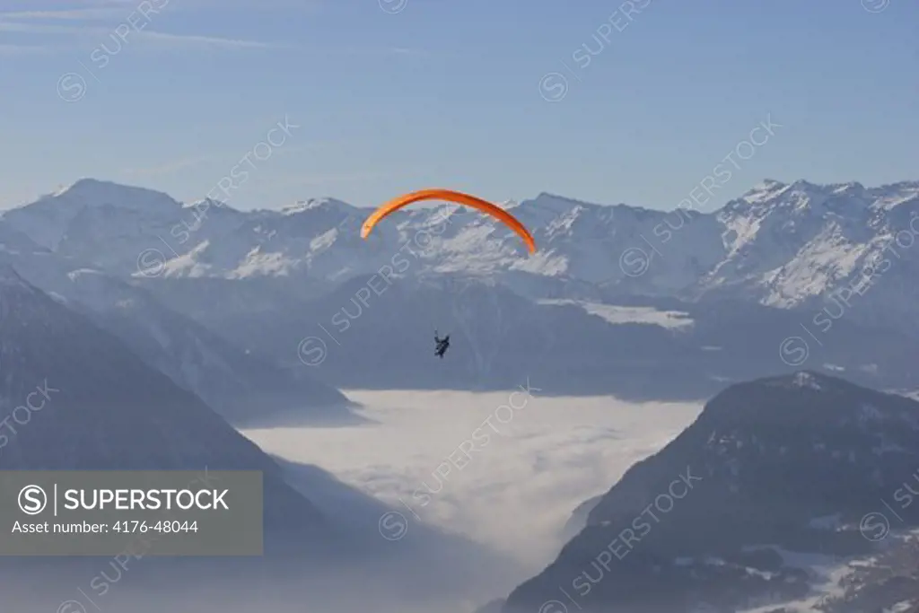 Paraglider soaring over the clouds in mountains