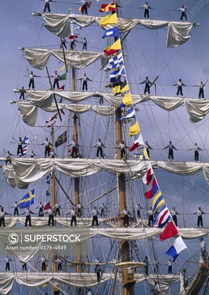 Sailors standing on the crossbars of a triple masted schooner