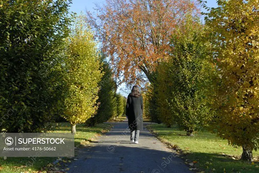 Woman walking in an autumn park somewhere in Copenhagen, Denmark.