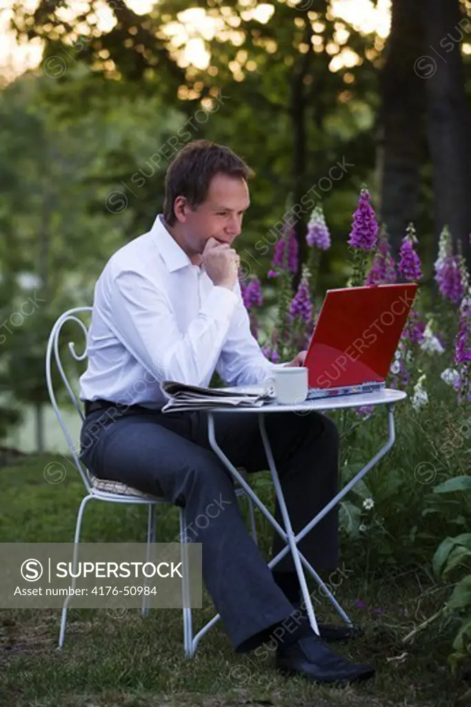 Man sitting outdoors looking at laptop.