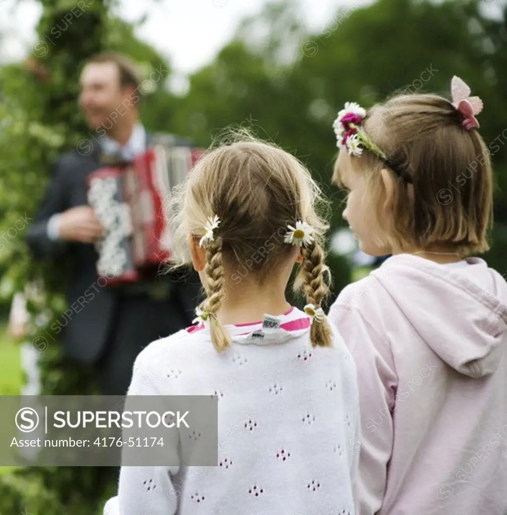 Two kids listening to a musician during midsummerfeast Sormland, Sweden