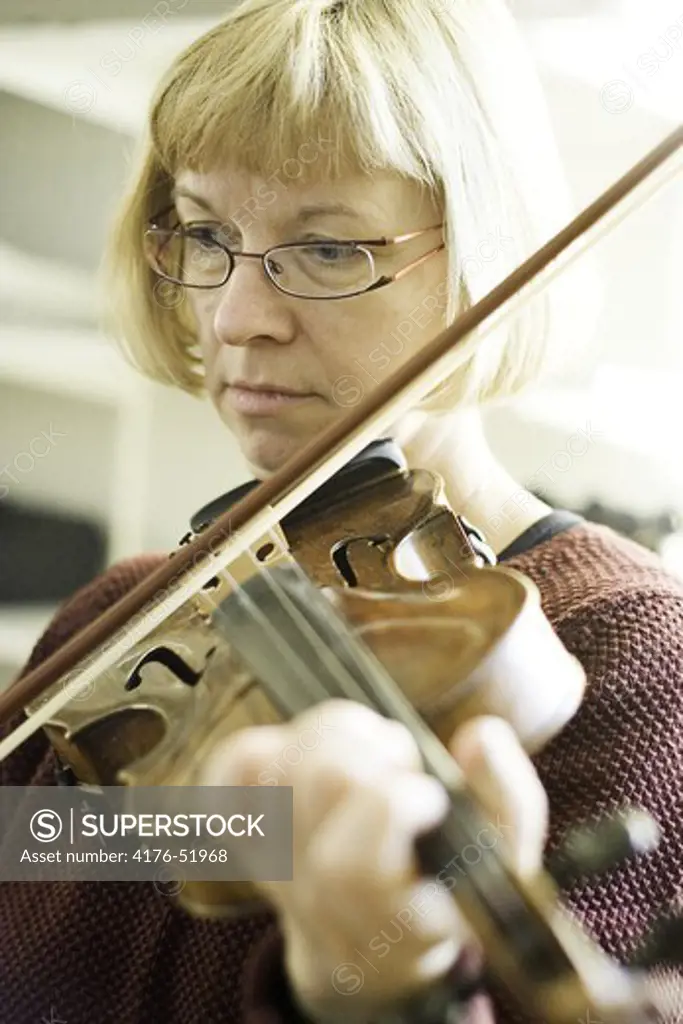 Medelålders dam spelar fiol koncentrerat