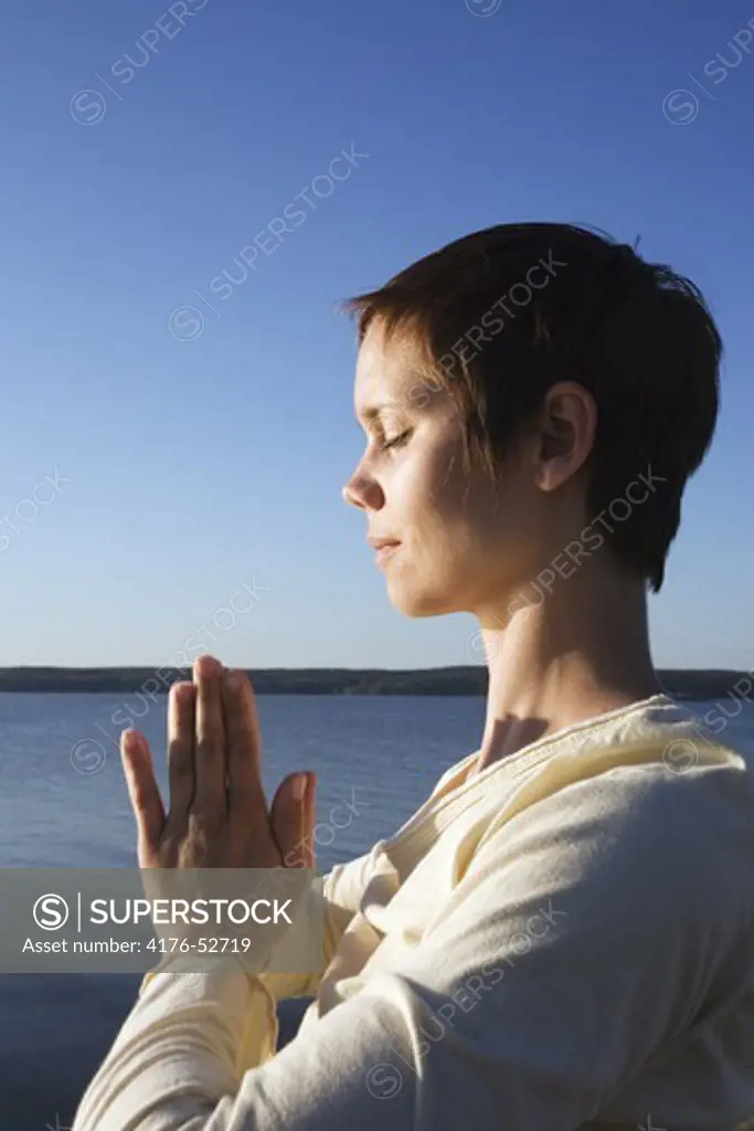 A woman practicing Qi gong by the water.