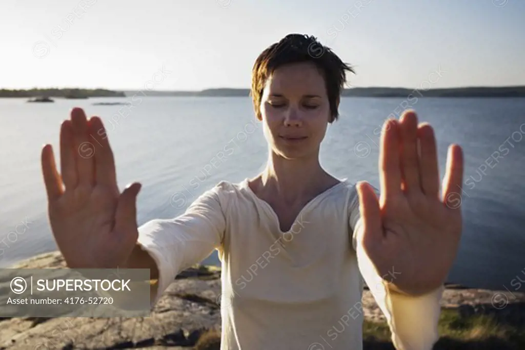 A woman practicing Qigong by the waterline.