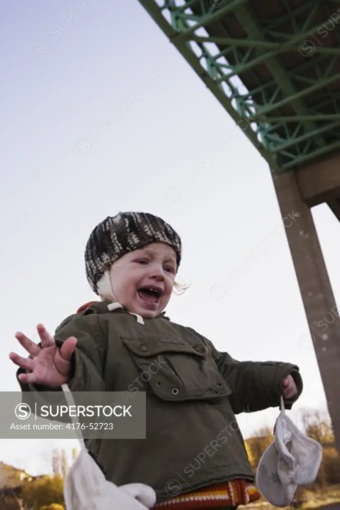 A child standing under a bridge screaming with fear.