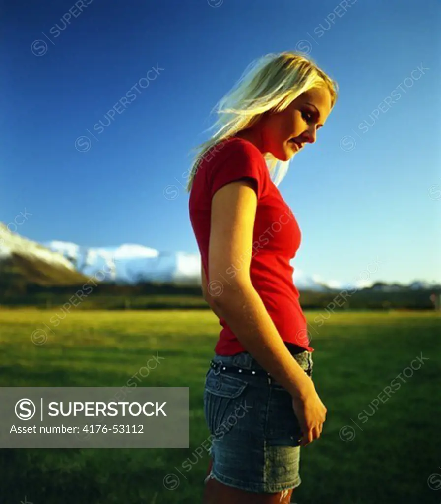 A woman in red top in a grassy field, Sandskeid, by Vífilsfell mountain, South-west Iceland