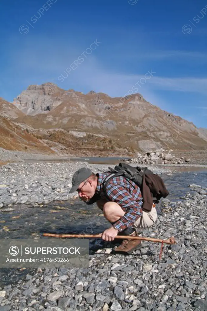 Hiker drinking water from a creek, Lac De Salanfe, Evionnaz, Valais Canton, Switzerland