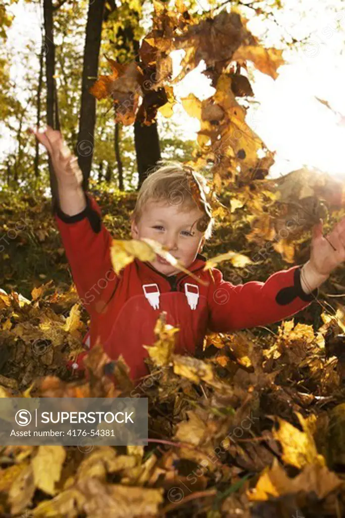Pojke kastar löv i luften.