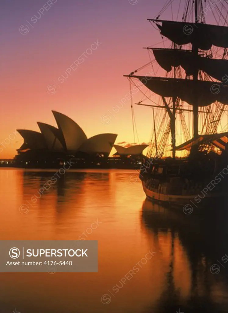 Sydney Opera House with schooner in Campbells Cove silhouetted at sunrise
