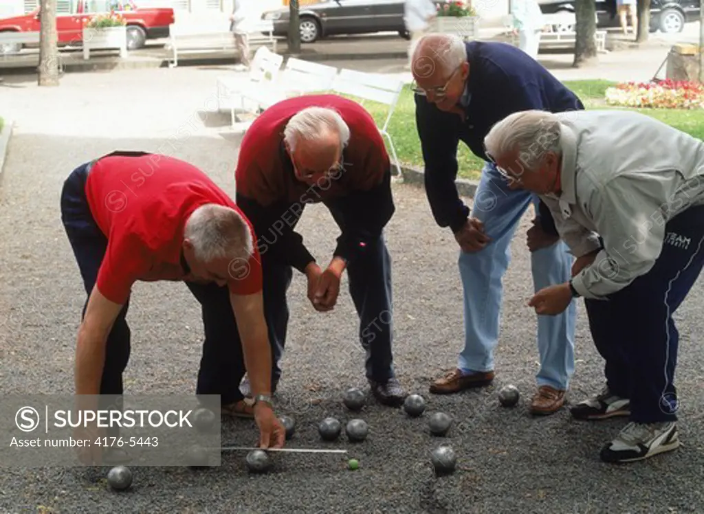 Four elderly gentlemen playing boules in park