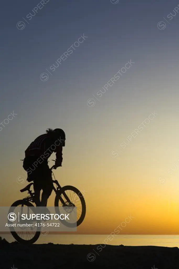 Silhouette of a person performing stunt on a bike, Sweden.