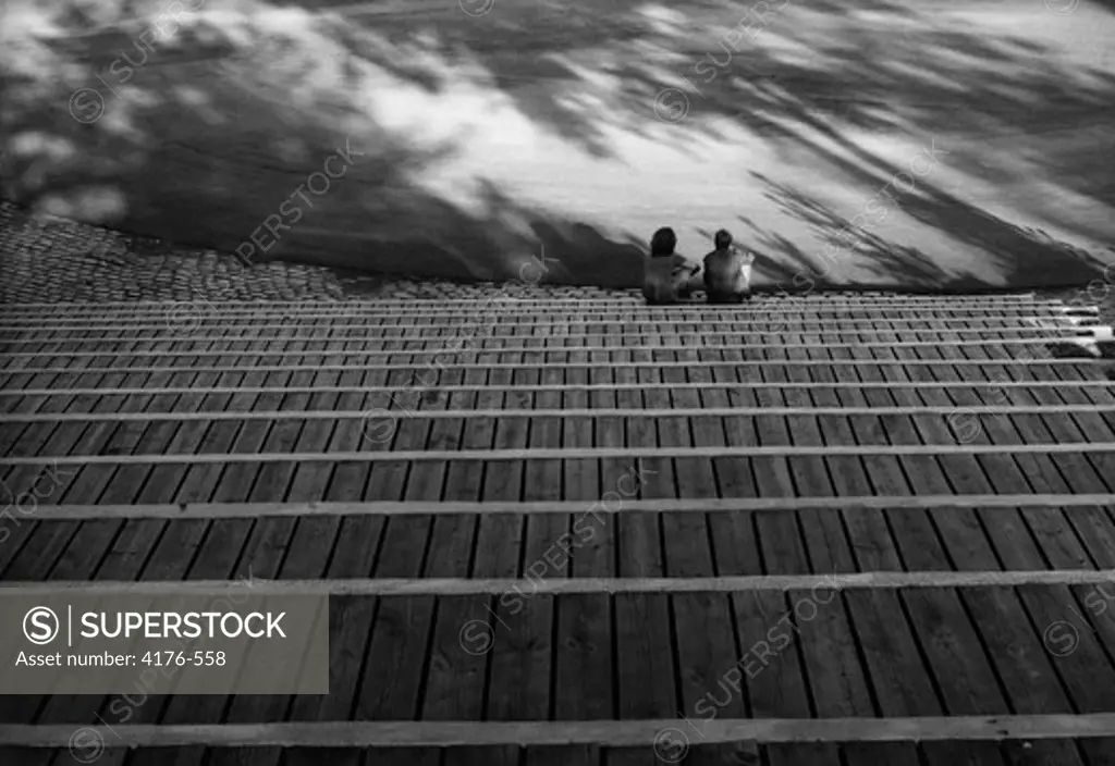 Two persons sitting on the bottom step of a grandstand. Stockholm