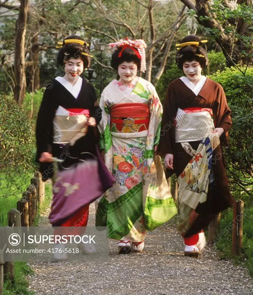 Geisha women in colorful kimonos on pathway in Tokyo park
