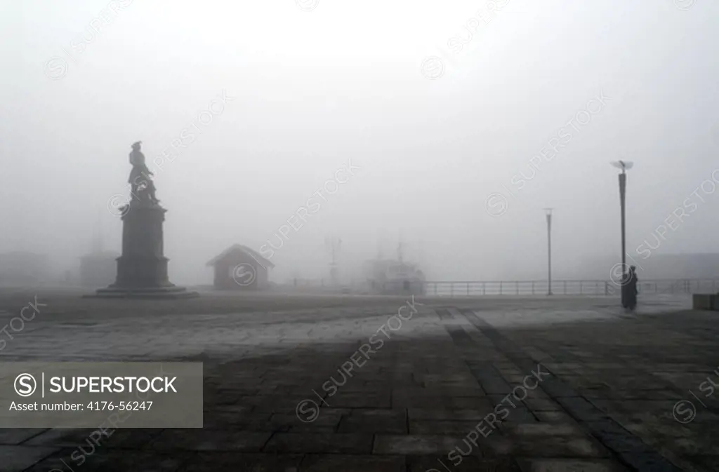 Statue and person in fog, seaside docks, Oslo, Norway