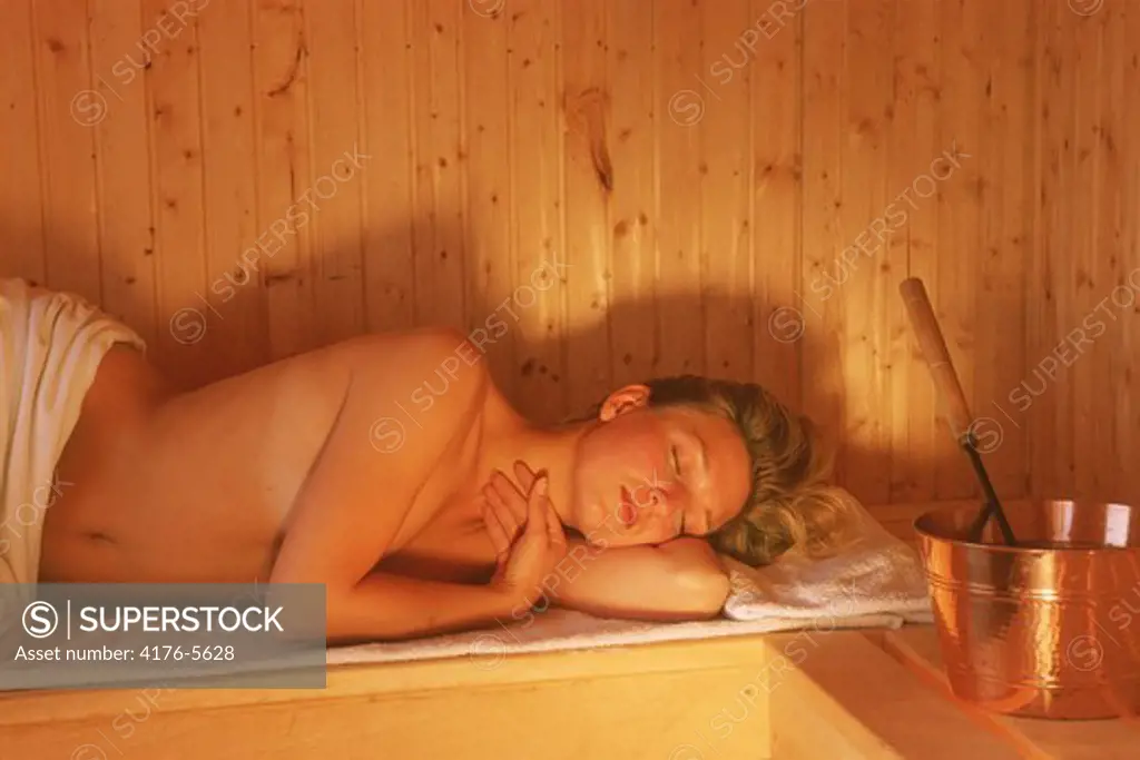Woman restiing in hot sauna made of wood
