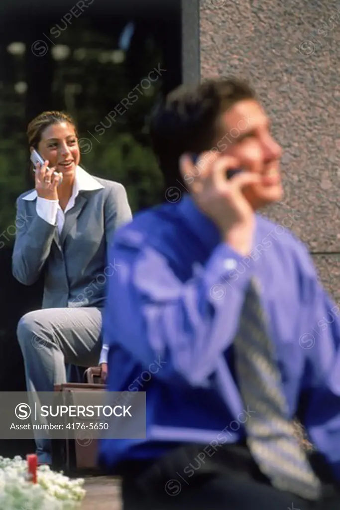 Businessman talking on cellphone with businesswoman behind