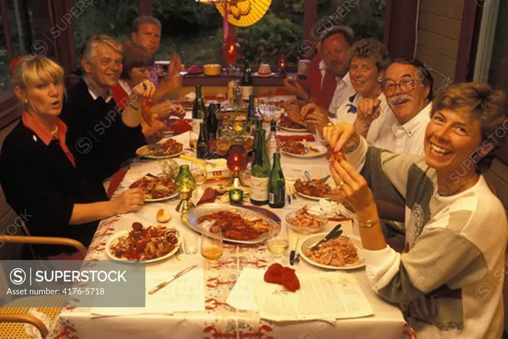Swedes laughing singing and drinking at traditional crayfish party