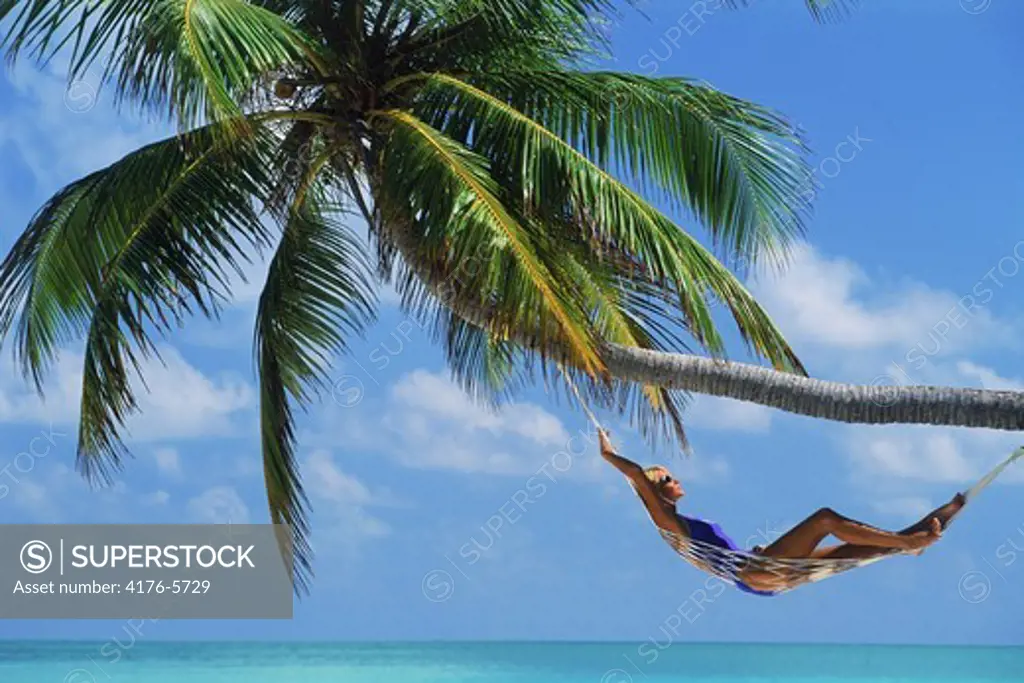 Woman relaxing in hammock under palm tree