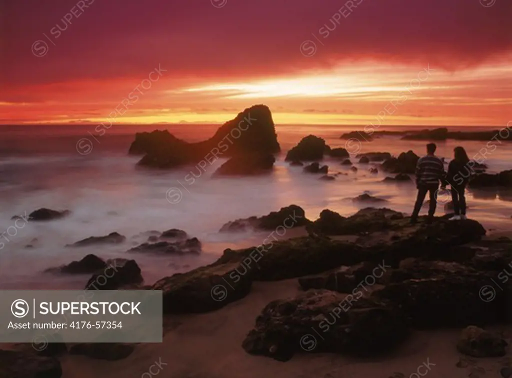 Couple standing by the beach at sunset
