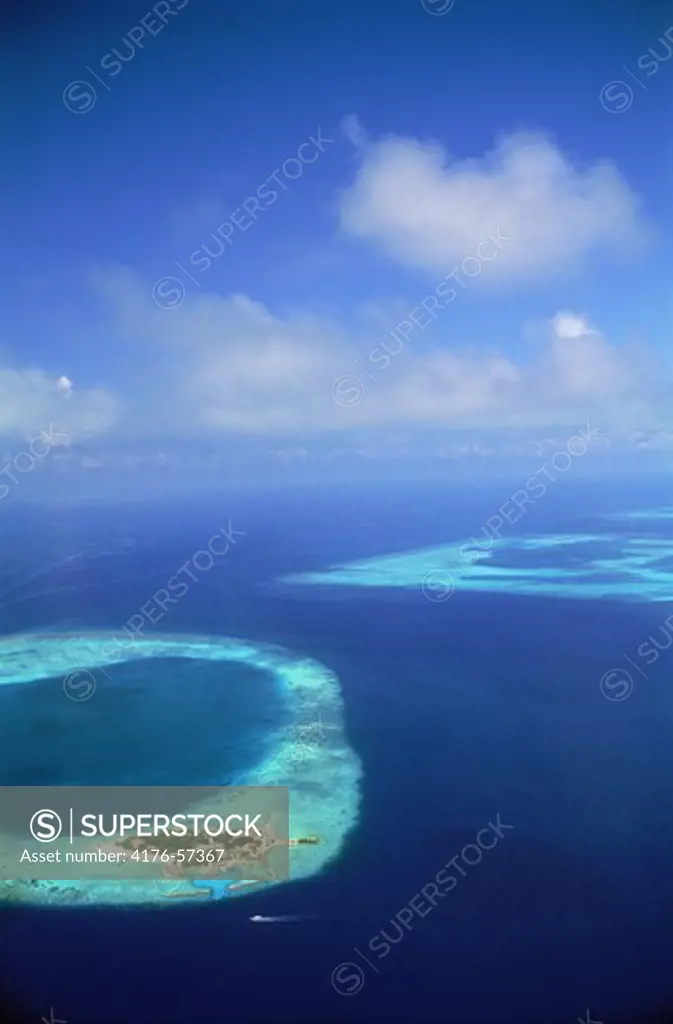 Aerial view of resort island encircled by reef and blue Indian Ocean in the Maldive Islands