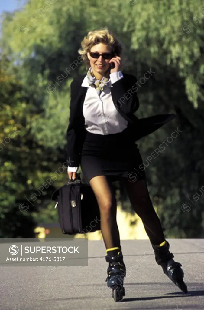 Woman with briefcase talking on cellphone while rollerblading to work