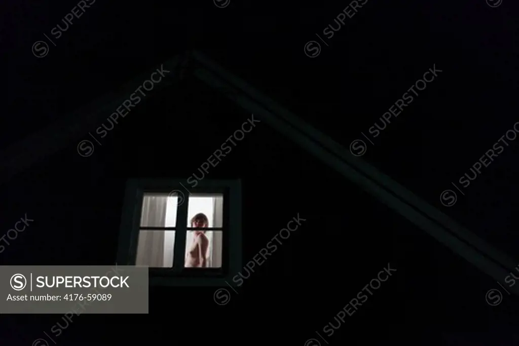 Naked young adult women in a window, Sweden.