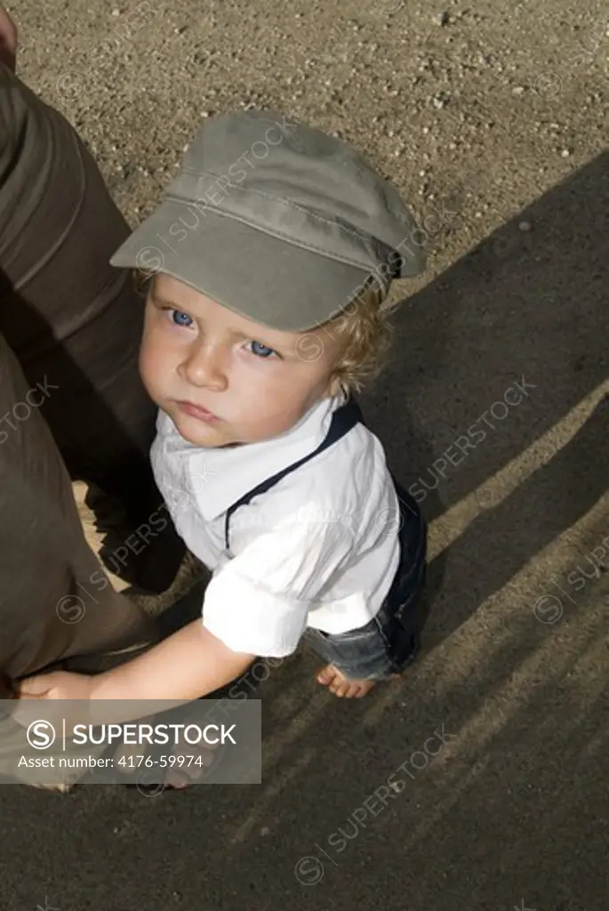 A child grabbing his mother's leggs