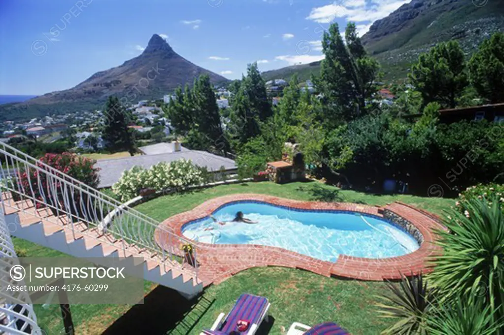 Woman in backyard swimming pool under Lion's Head mountain at Camps Bay in Cape Town  South Africa