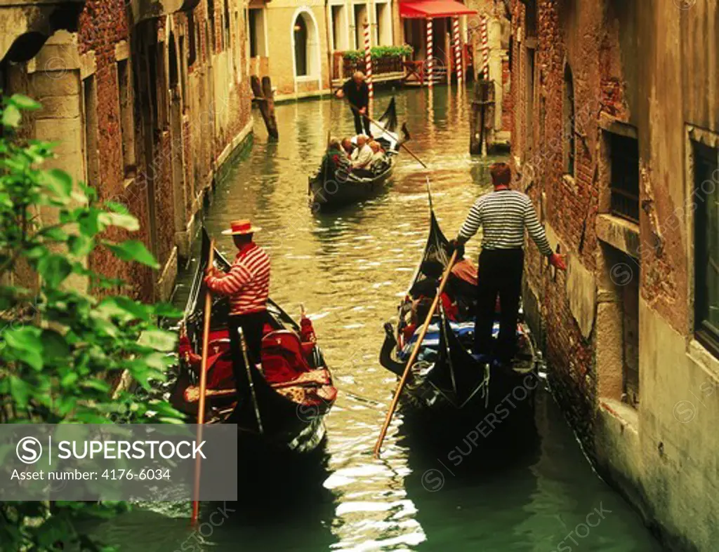 Gondolas passing on narrow canal in Venice
