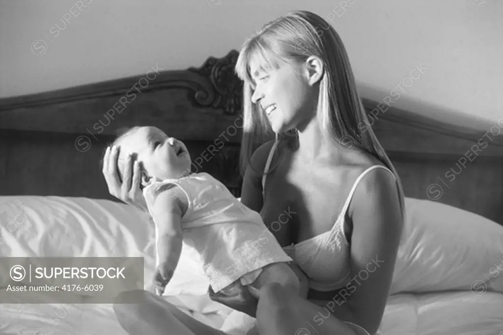 Mother holding 6 month old baby in bedroom