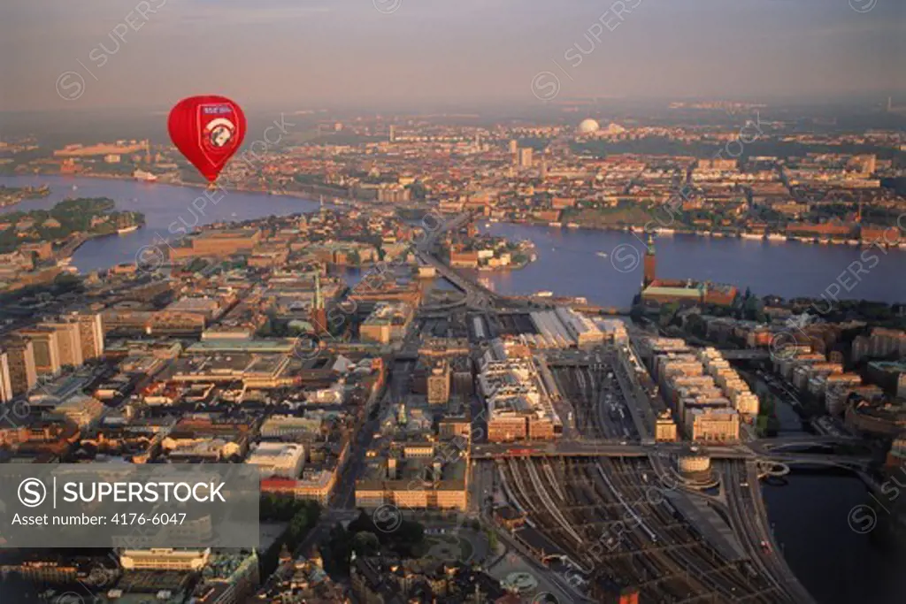 Red hot air balloon floating over Stockholm at sunset
